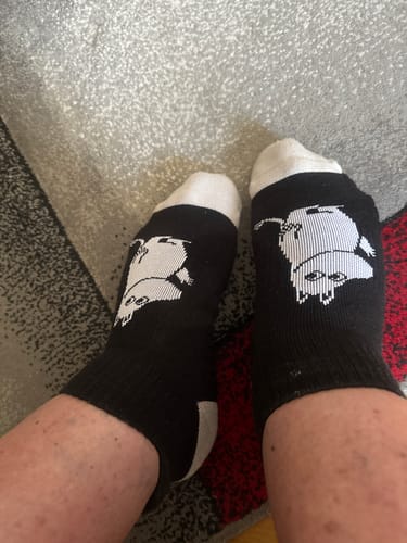 Kundens svarta Mumin ankelstödstrumpor med Mumin-motiv på fötterna.