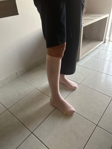 Kundens ljusrosa Diasocks stödstrumpor på benen, visar hur bra de sitter vid användning.