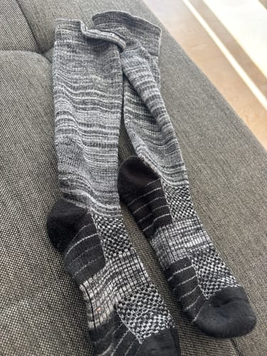 Anmelders grå og sorte Diasocks støttestrømper liggende på en grå sofa.